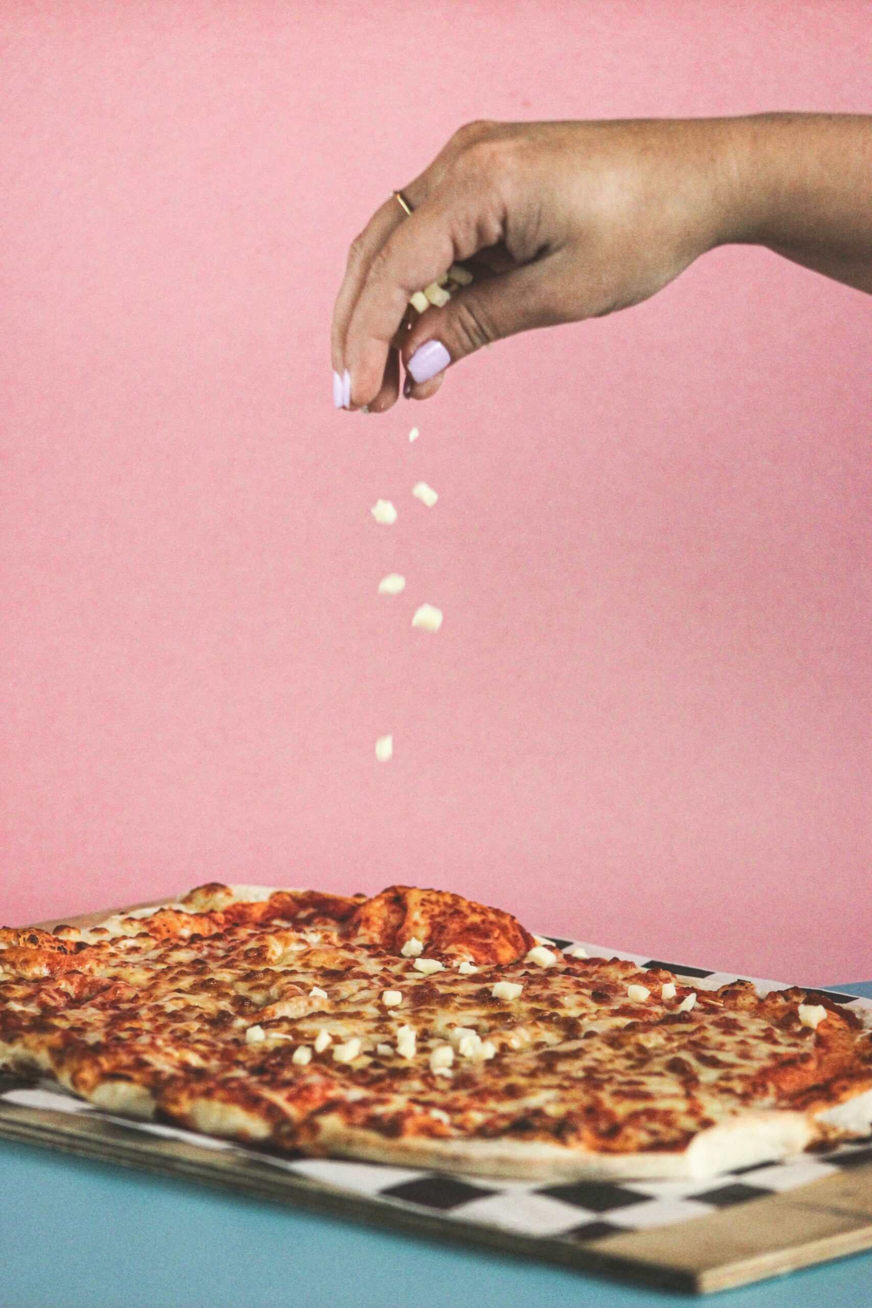 person holding pizza with cheese and ham